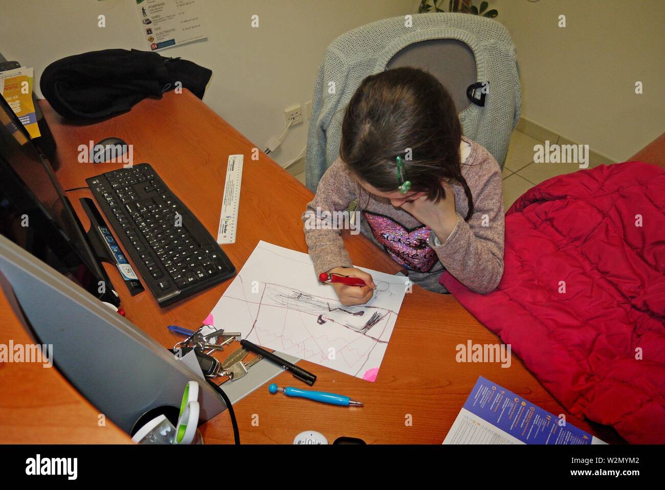 A young girl draws at her mother´s office desk. Stock Photo