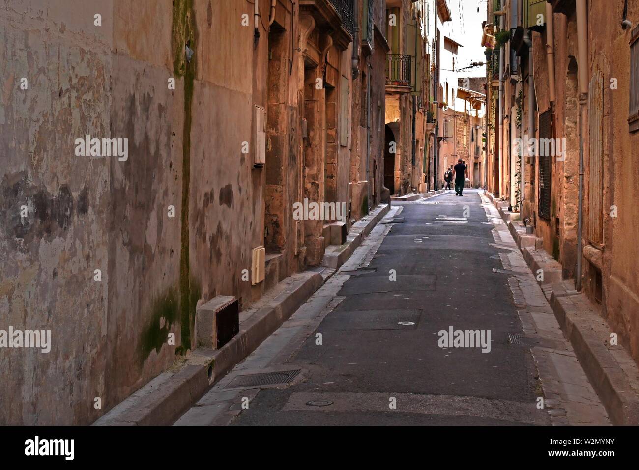 A man walks down one of Renaissance era streets of Pezenas France. Stock Photo