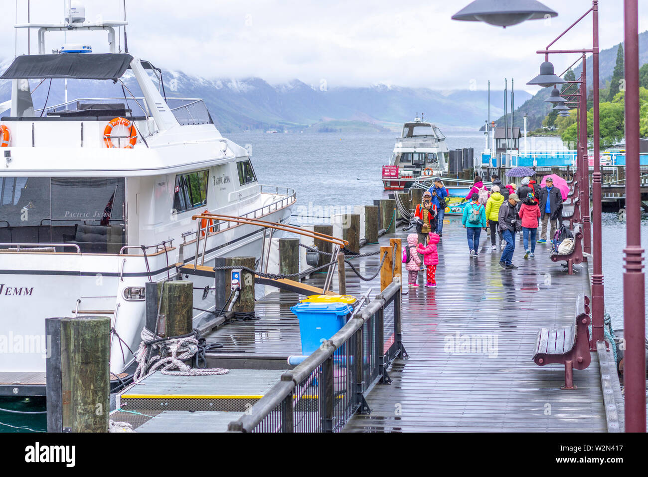 Tourists walking on Queenstown wharf, Lake Wakatipu, Queenstown New Zealand Stock Photo
