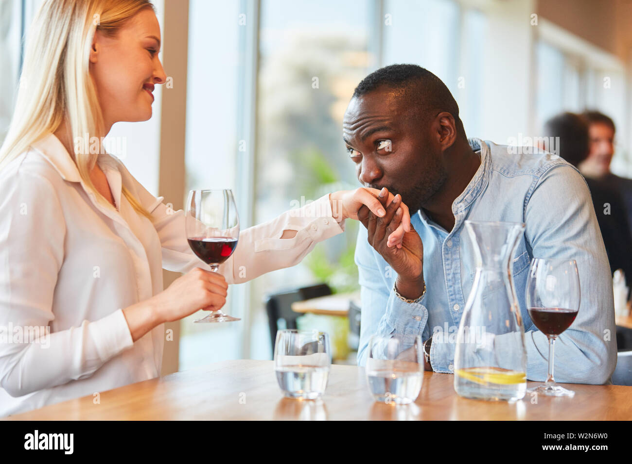Young African man gives his girlfriend a hand kiss in the restaurant Stock Photo
