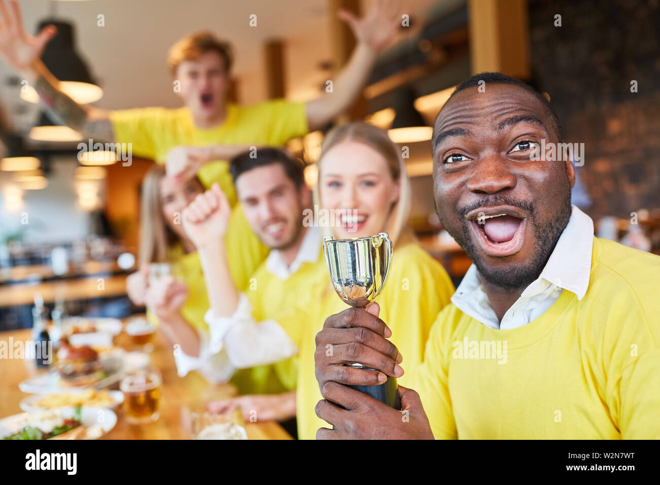 Group sports fans with a small winning trophy in a pub or restaurant