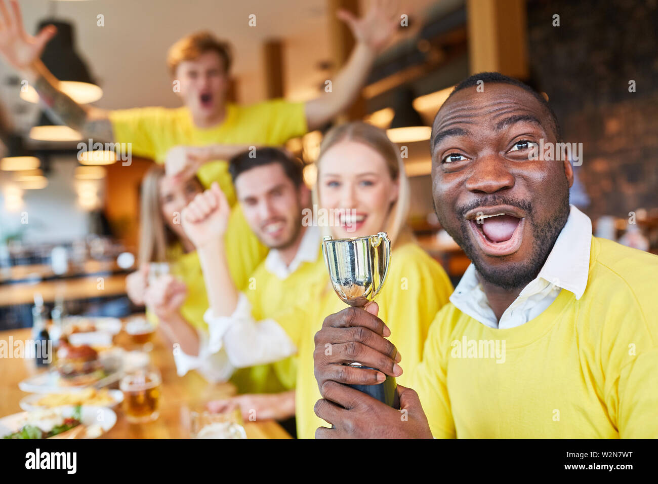 Group sports fans with a small winning trophy in a pub or restaurant Stock Photo