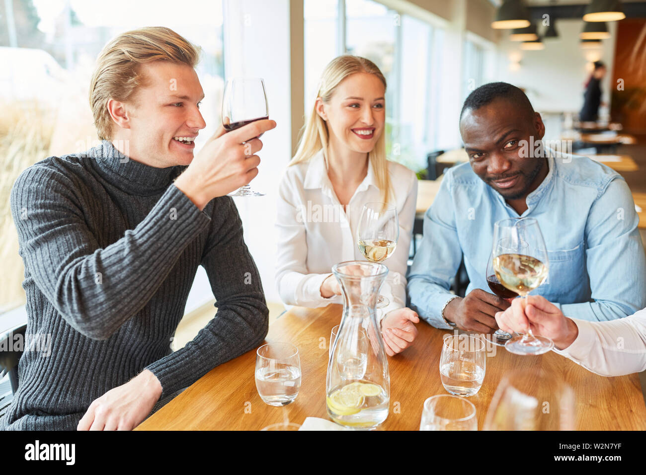 Young man with friends as a guest in the restaurant while tasting with red wine Stock Photo