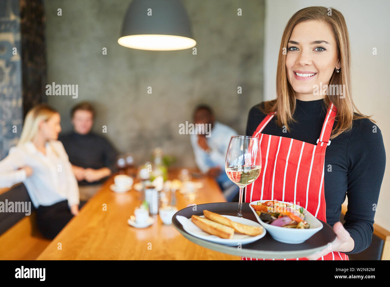 Friendly young waitress with appetizers makes training in the restaurant Stock Photo