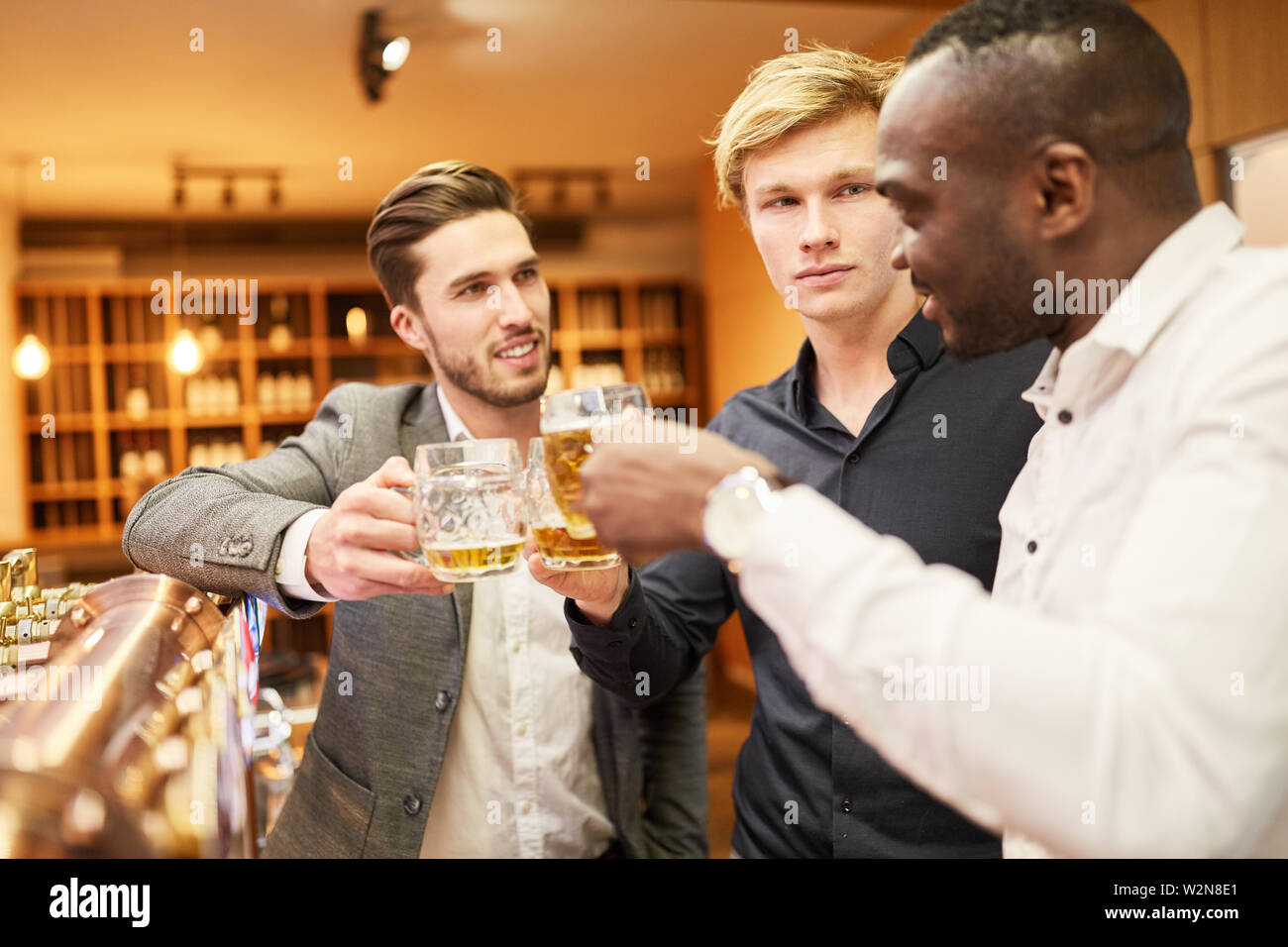Men brag to beer at the counter during a pub crawl as a men's night Stock Photo