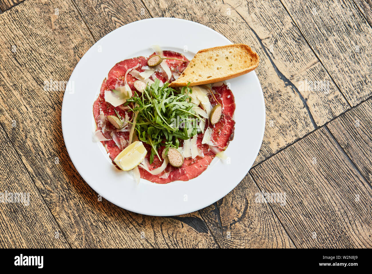Ham plate with stuffed olives and rocket on a rustic table Stock Photo