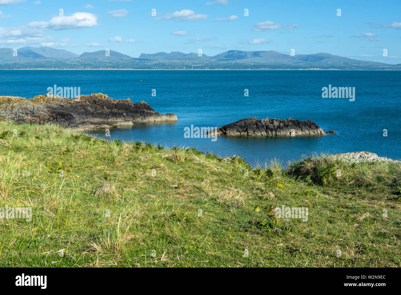 Menai Strait and Snowdonia mountains seen from rocky coast of Anglesey Island - 1 Stock Photo