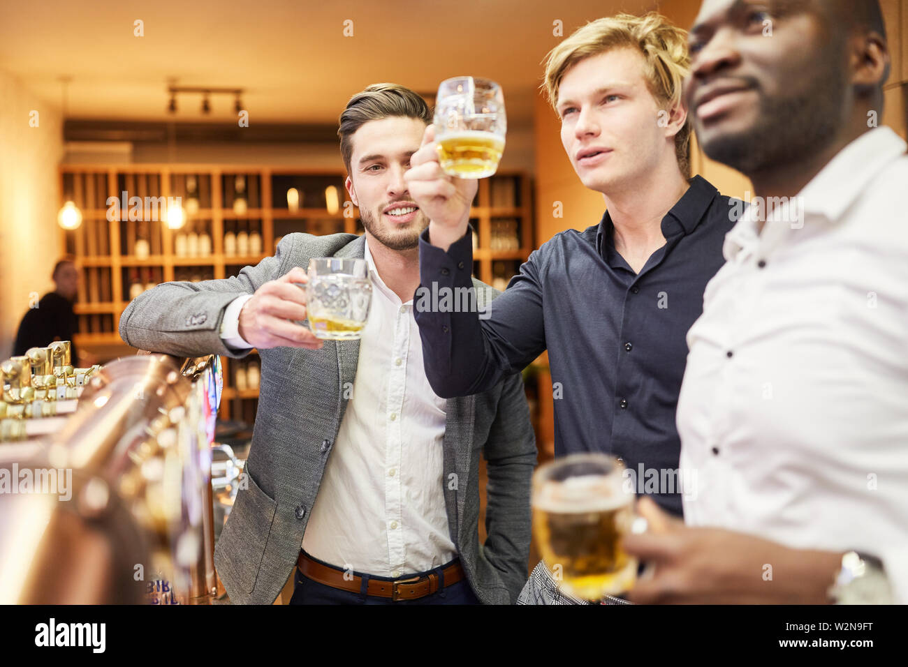 Men as friends and mates while drinking beer together in the pub at the bar Stock Photo