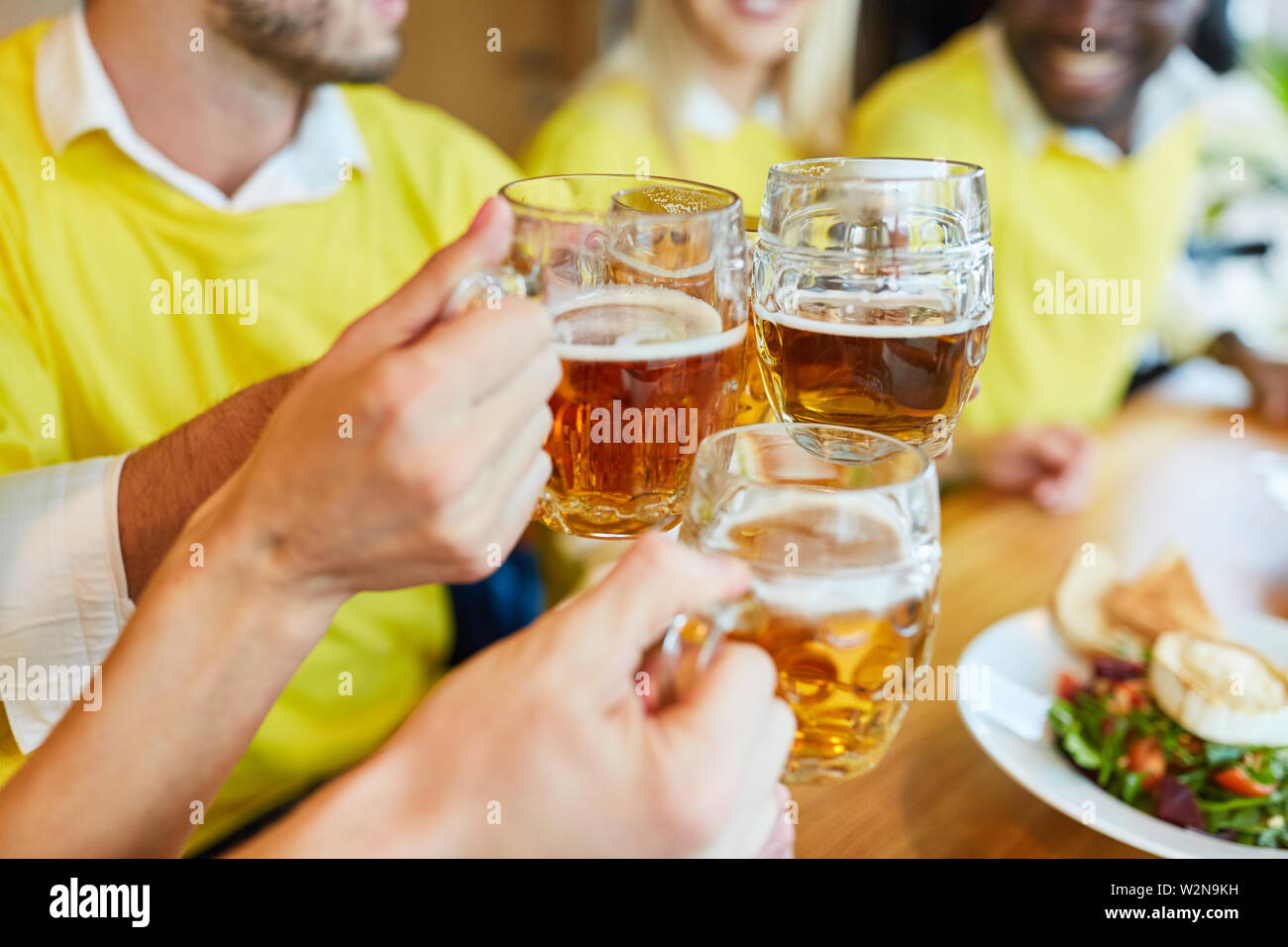 Hands hold beer glass while toasting in a bar or restaurant Stock Photo