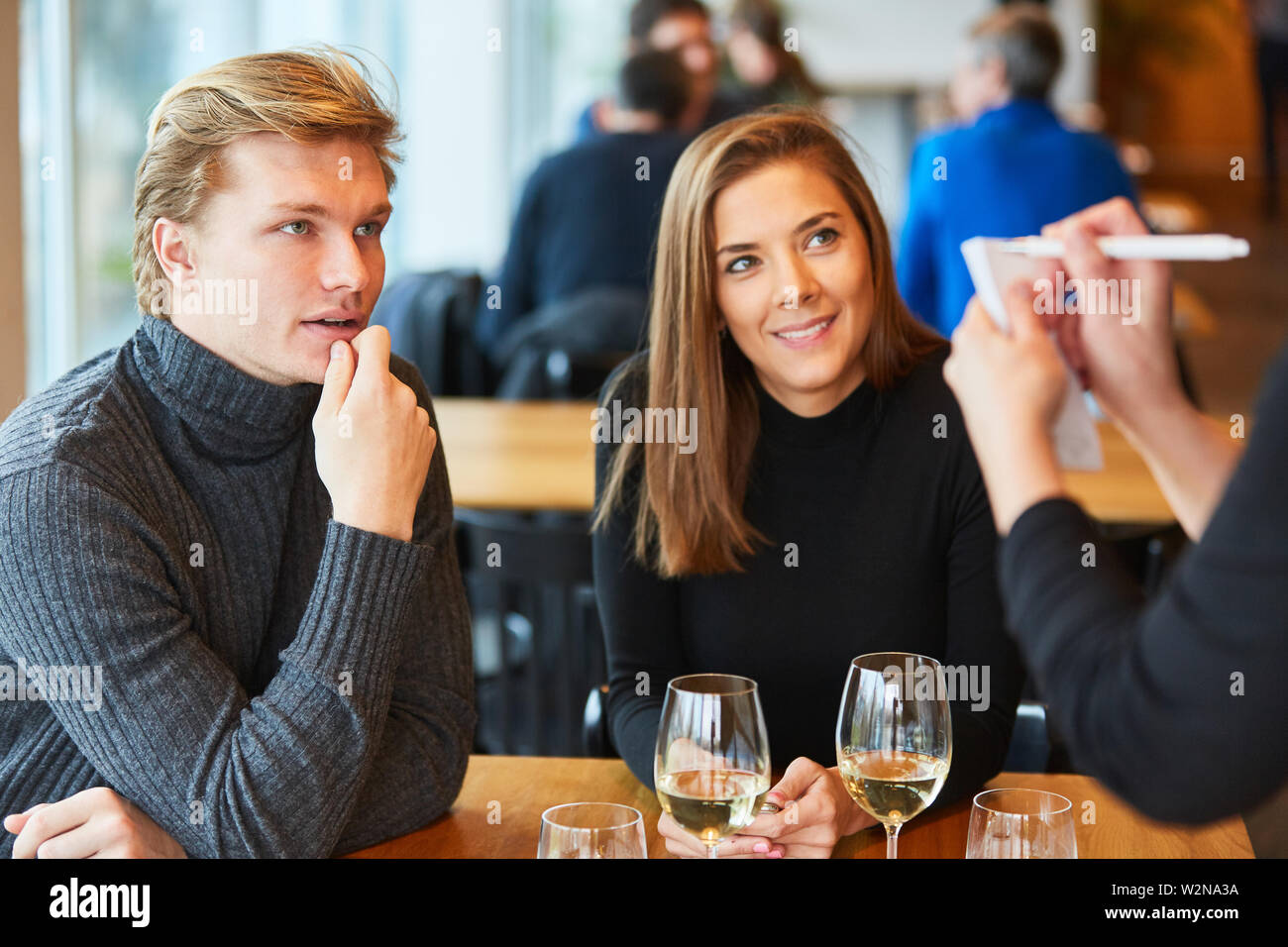Young man with girlfriend places his order in the bistro or restaurant Stock Photo