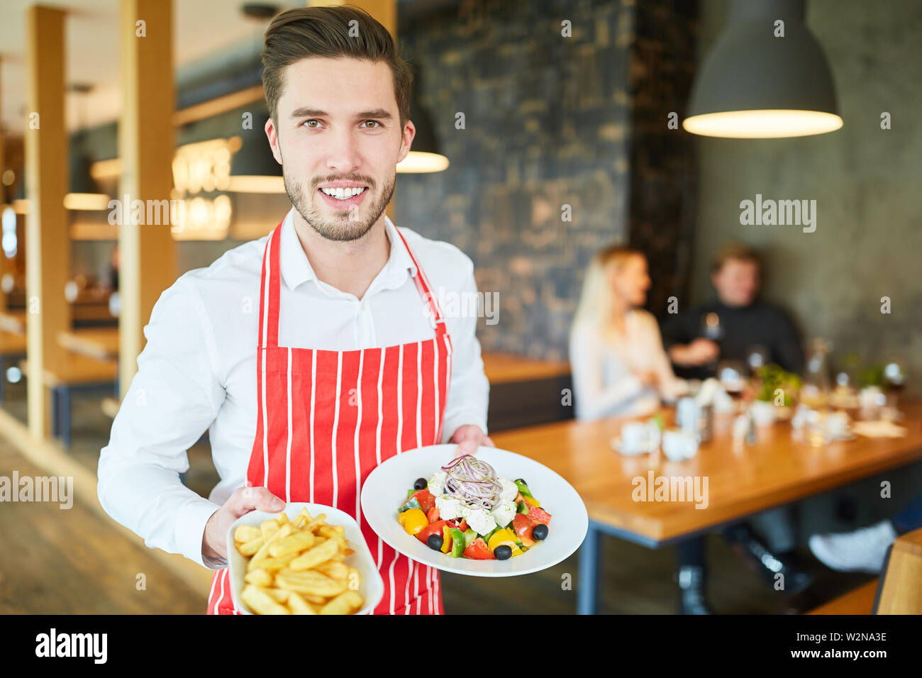 Young man as a friendly waiter in the restaurant serves appetizers Stock Photo