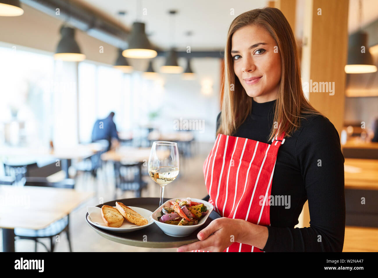 Young woman with tray makes training to waitress in the restaurant Stock Photo