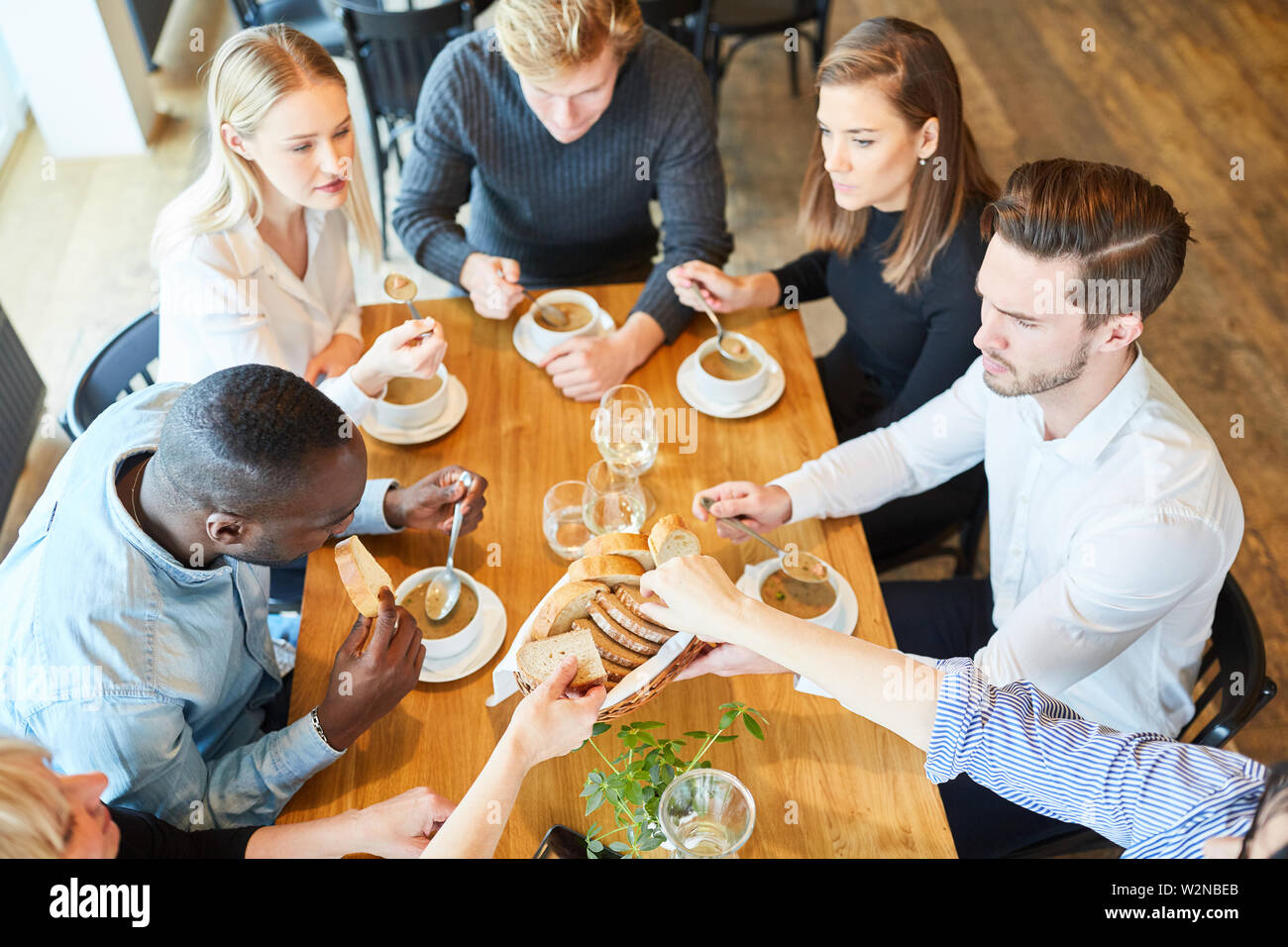 Group of young people eating soup as an appetizer in the restaurant Stock Photo
