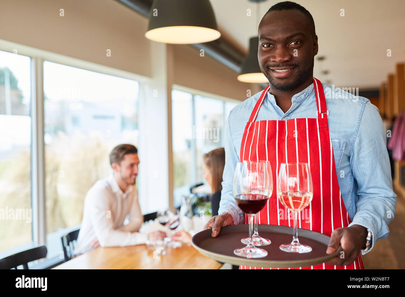 African man as a waiter serving glasses with wine on a tray Stock Photo