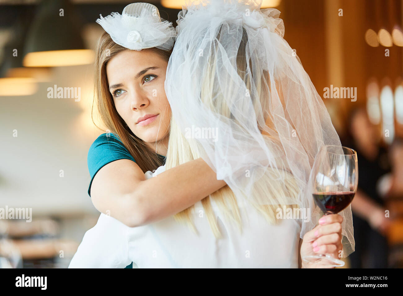 Melancholy woman hugs bride with bridal veil at hen party Stock Photo
