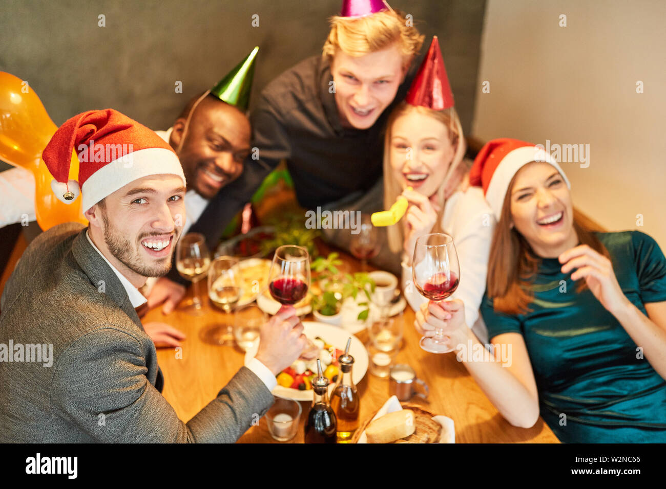 Young people at a Christmas party celebrate funny and happy with a lot of red wine Stock Photo