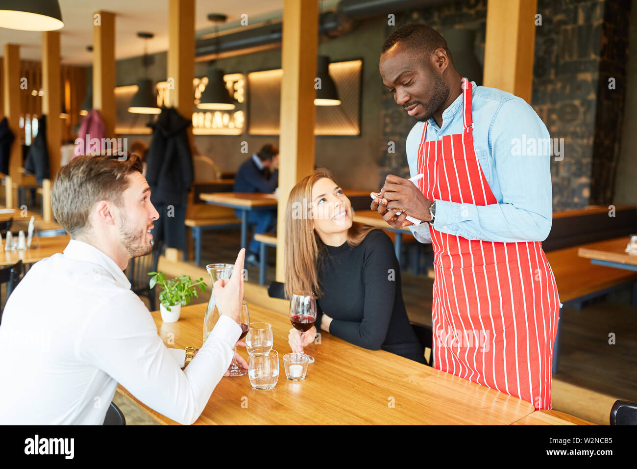 African waiter records order of guests couple on a notepad Stock Photo