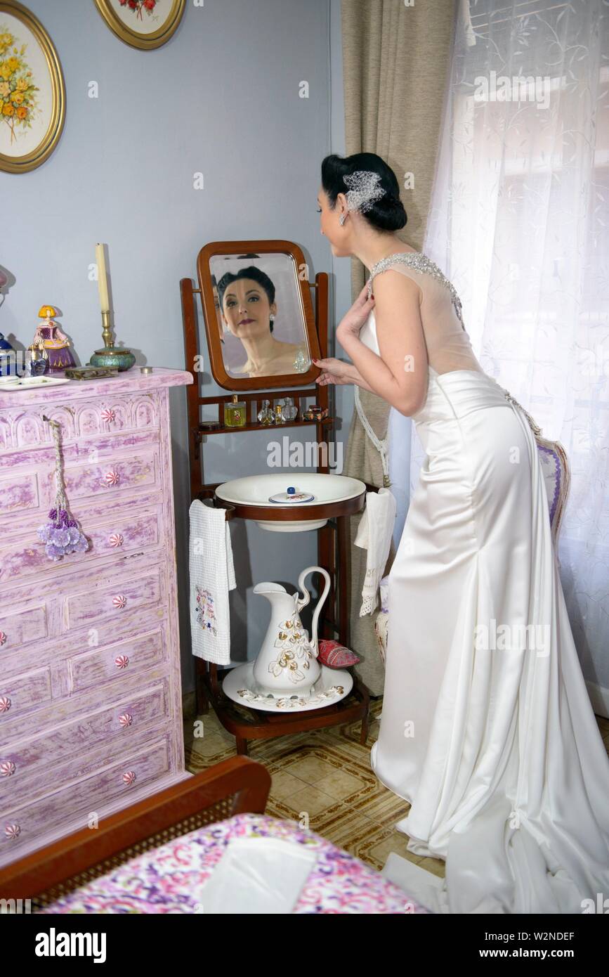 The Bride Dresses In Front Of The Antique Dresser On The Day Of