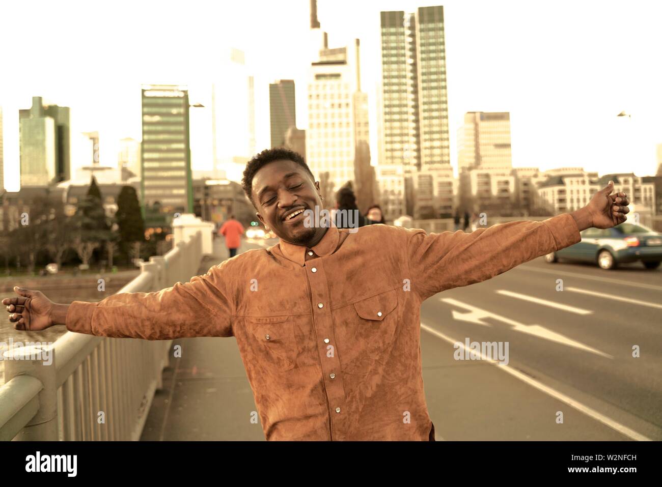 eased African man with open arms at street in city, carefree, in Frankfurt, Germany. Stock Photo