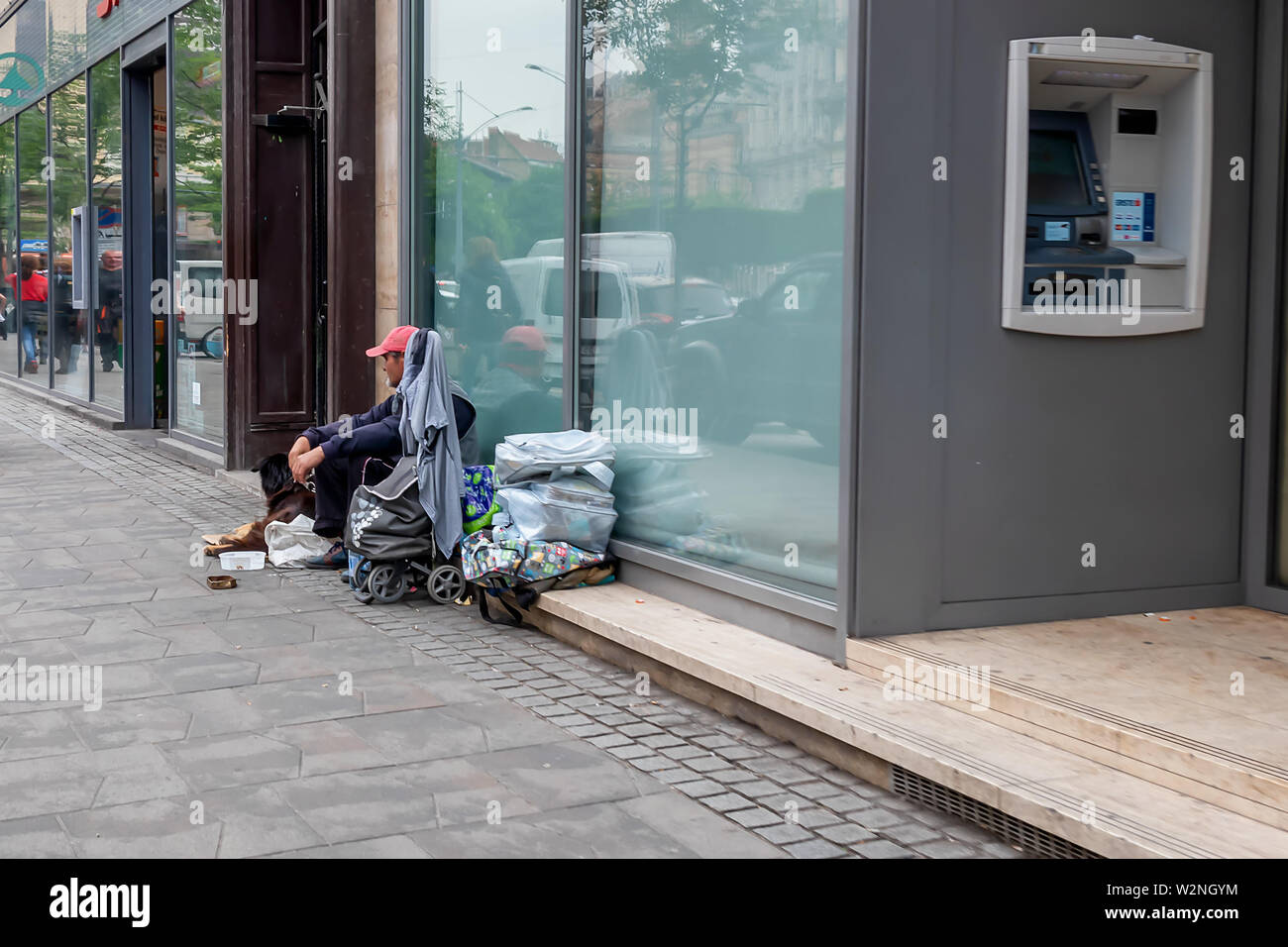 Budapest, Hungary - May 27, 2019 :  Homeless man with dog sitting by the wall of the building on the street of Budapest, Hungary Stock Photo
