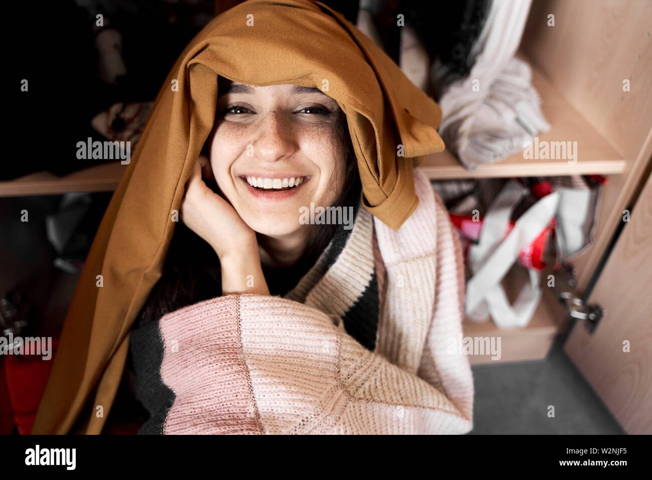 young smiling woman overwhelmed by her clothes Stock Photo