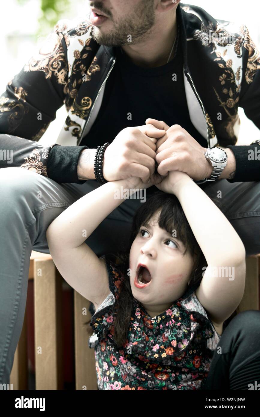 father holding hands of astonished daughter child yawning Stock Photo