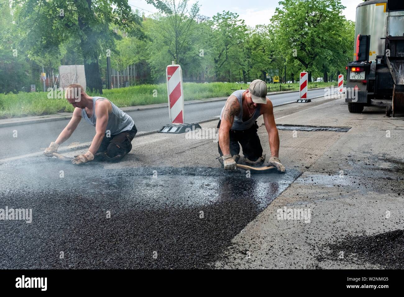 Berlin, Germany. Male Road Workers hard at work to patch a piece of road inside the German Capitol. All work is done by hand and manual labour, Stock Photo