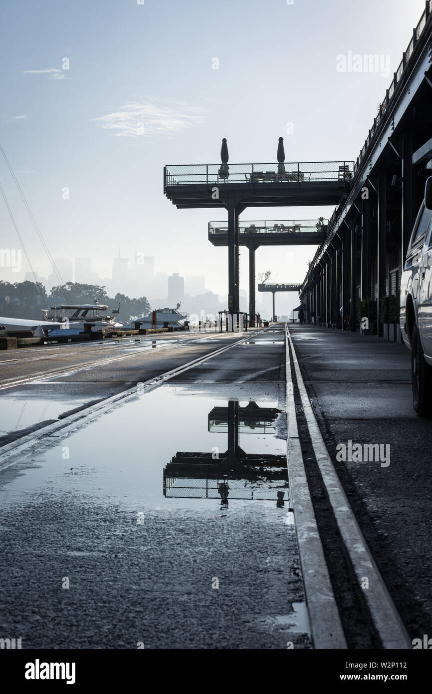 Low angle urbanscape at Jones Bay Wharf. North Sydney visible in the through the early morning haze in the background. Sydney NSW. June 2019 Stock Photo