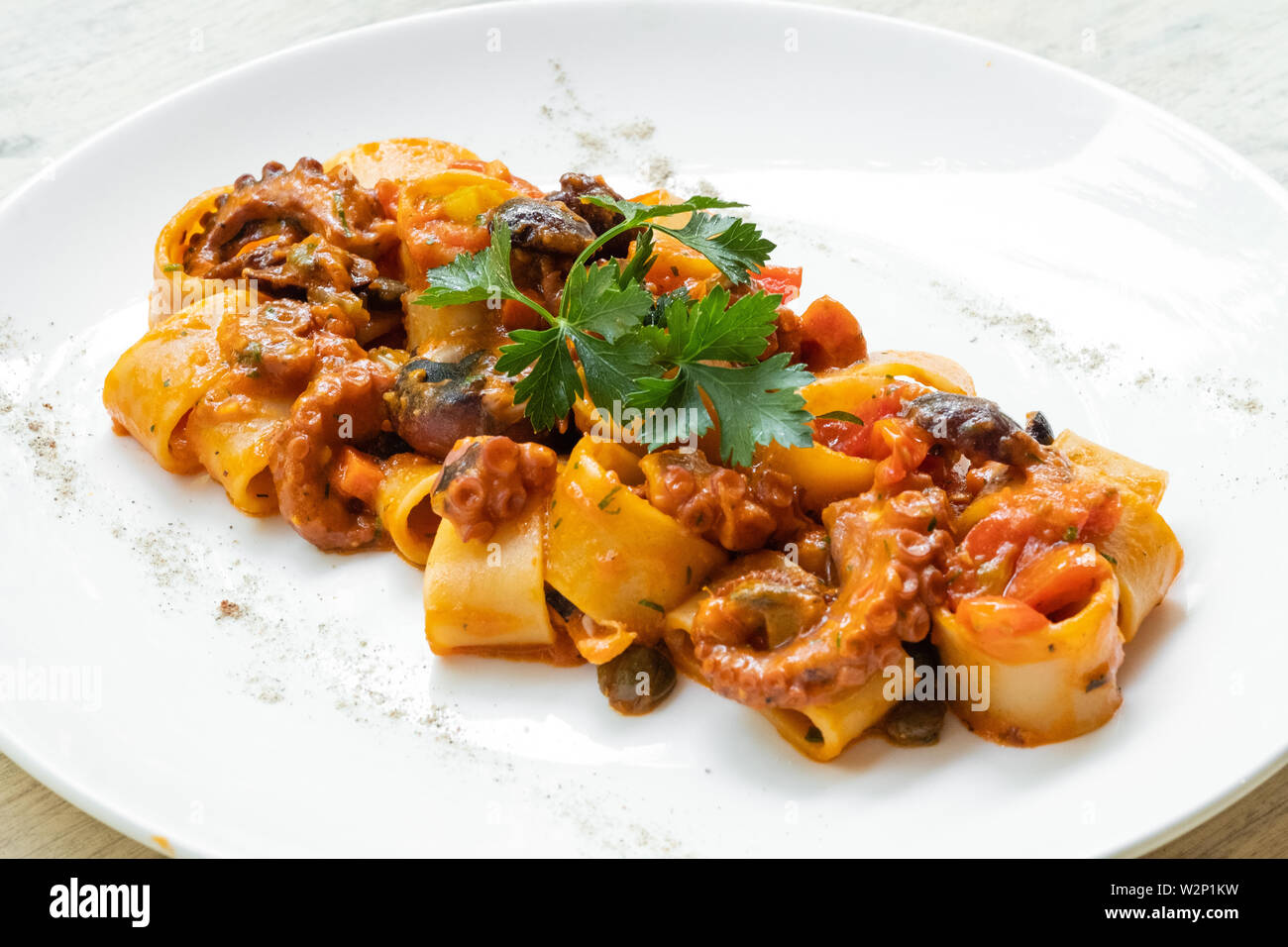 close up of calamarata octopus italian traditional sicilian pasta homemade seafood sauce with tomato,basil,parsley,herbs,chilly prepared by profession Stock Photo