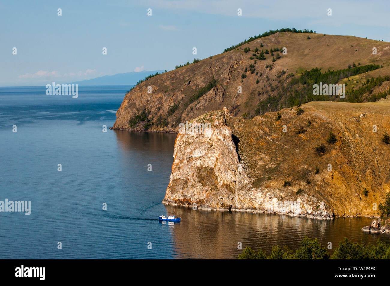 Small ship on the background of large rocks.. Boat sails on Lake Baikal. Stock Photo