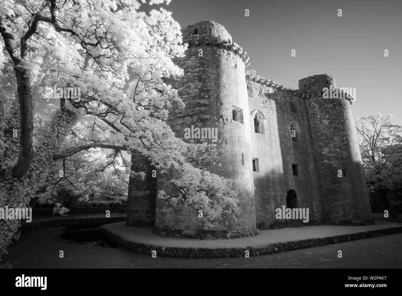 An infrared black and white image of Nunney Castle and moat in the village of Nunney, Somerset, England. Stock Photo
