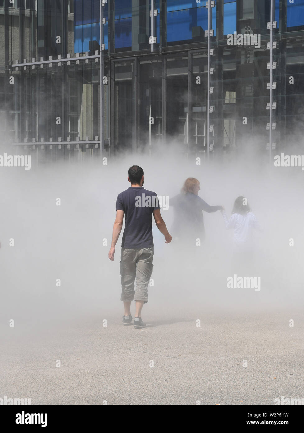 Karlsruhe, Germany. 10th July, 2019. In front of the Center for Art and Media (ZKM), the fog sculpture 'CLOUD WALK @ZKM. Fog Sculpture #10731' by the artist Fujiko Nakaya. The work is part of the exhibition 'Negativer Raum Skulptur und Installation im 20./21. Jahrhundert' (Negative Space Sculpture and Installation in the 20th/21st Century) which lasts until 11.08.2019. The fog shows up during the opening hours from Wednesday to Sunday in the time 10.00 am to 18.00 pm every full hour for about eight minutes. Credit: Uli Deck/dpa/Alamy Live News Stock Photo