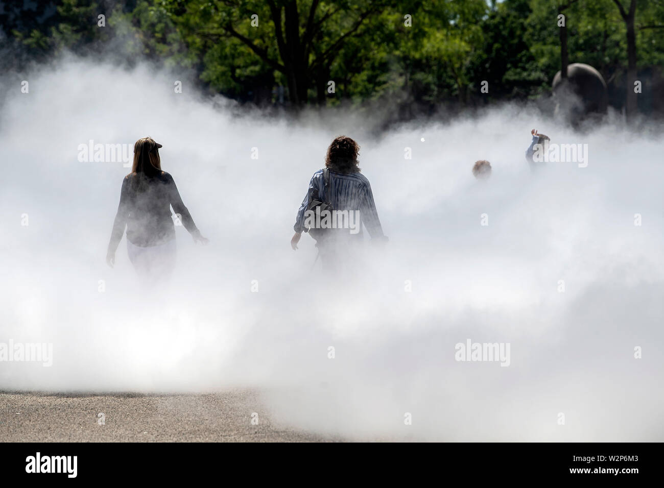 Karlsruhe, Germany. 10th July, 2019. In front of the Center for Art and Media (ZKM), the fog sculpture 'CLOUD WALK @ZKM. Fog Sculpture #10731' by the artist Fujiko Nakaya. The work is part of the exhibition 'Negativer Raum Skulptur und Installation im 20./21. Jahrhundert' (Negative Space Sculpture and Installation in the 20th/21st Century), which lasts until 11.08.2019. The fog shows up during the opening hours from Wednesday to Sunday in the period 10.00 am to 18.00 pm every full hour for about eight minutes. Credit: Uli Deck/dpa/Alamy Live News Stock Photo
