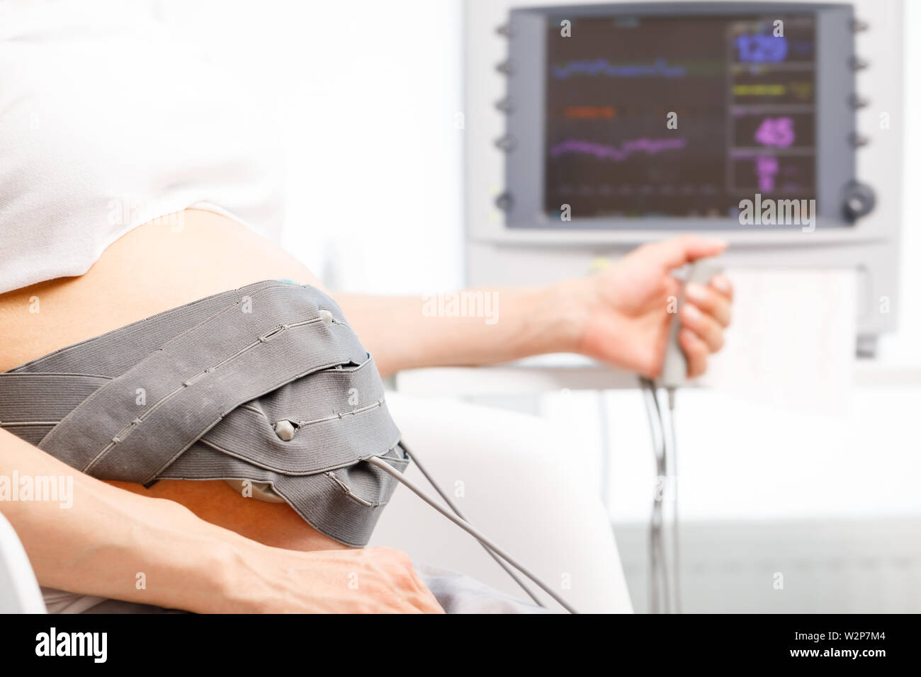 Pregnant woman sitting in clinic performing cardiotocography (CTG). The