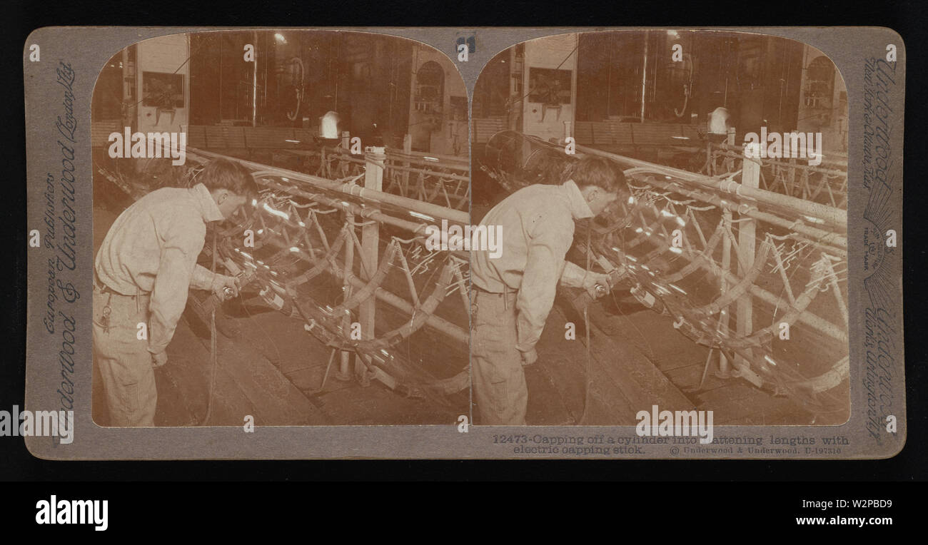 Capping off a cylinder into flattening lengths with electric capping stick.; Underwood & Underwood Stereographs of Manufacturing Industries,  Set 2 - Making glass sheets from cylinders,  Image 10 - Capping off a cylinder into flattening lengths with electric capping stick.  These stereographs were created and sold as a set for educational use by Underwood & Underwood, a maker of stereoscopic images and equipment. This set was produced between 1895, when the educational unit was established, and 1921, when the company was sold. Stock Photo