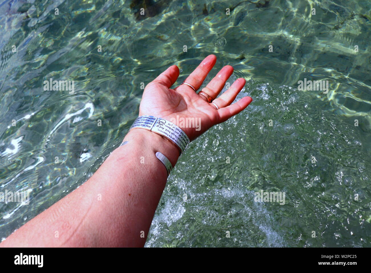 Woman's hand with silver bracelets and rings, splashing in ocean water Stock Photo
