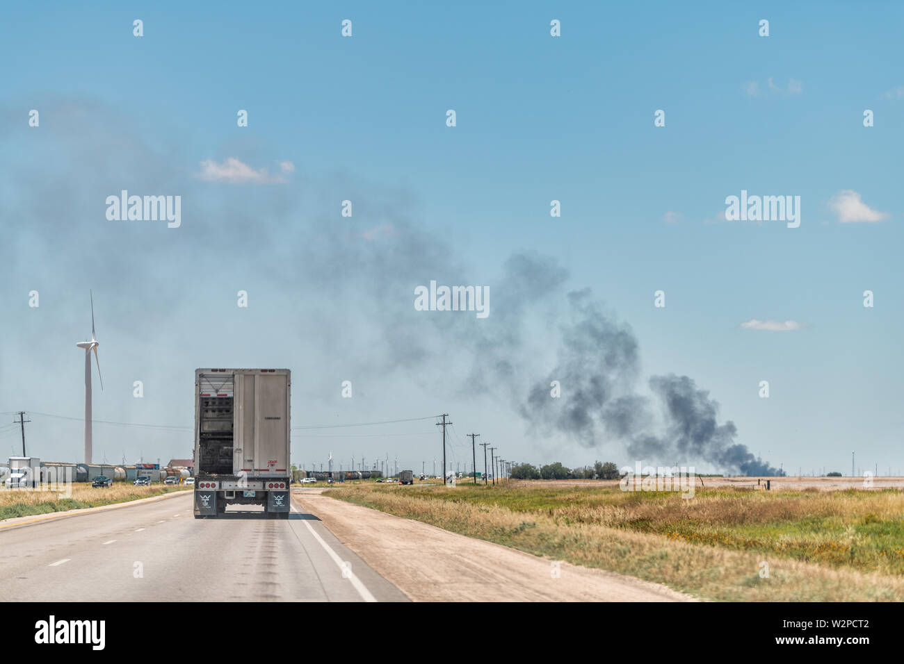 Sweetwater, USA - June 7, 2019: Interstate highway road i20 in Texas countryside with truck and fire in distance horizon Stock Photo