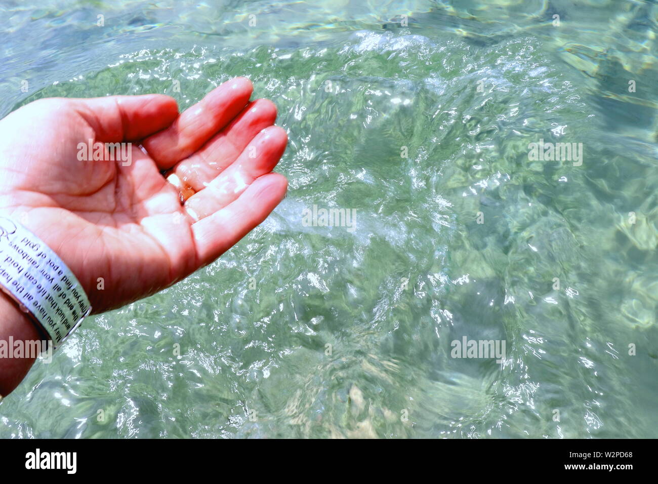 Woman's hand with silver bracelets and rings, splashing in ocean water Stock Photo