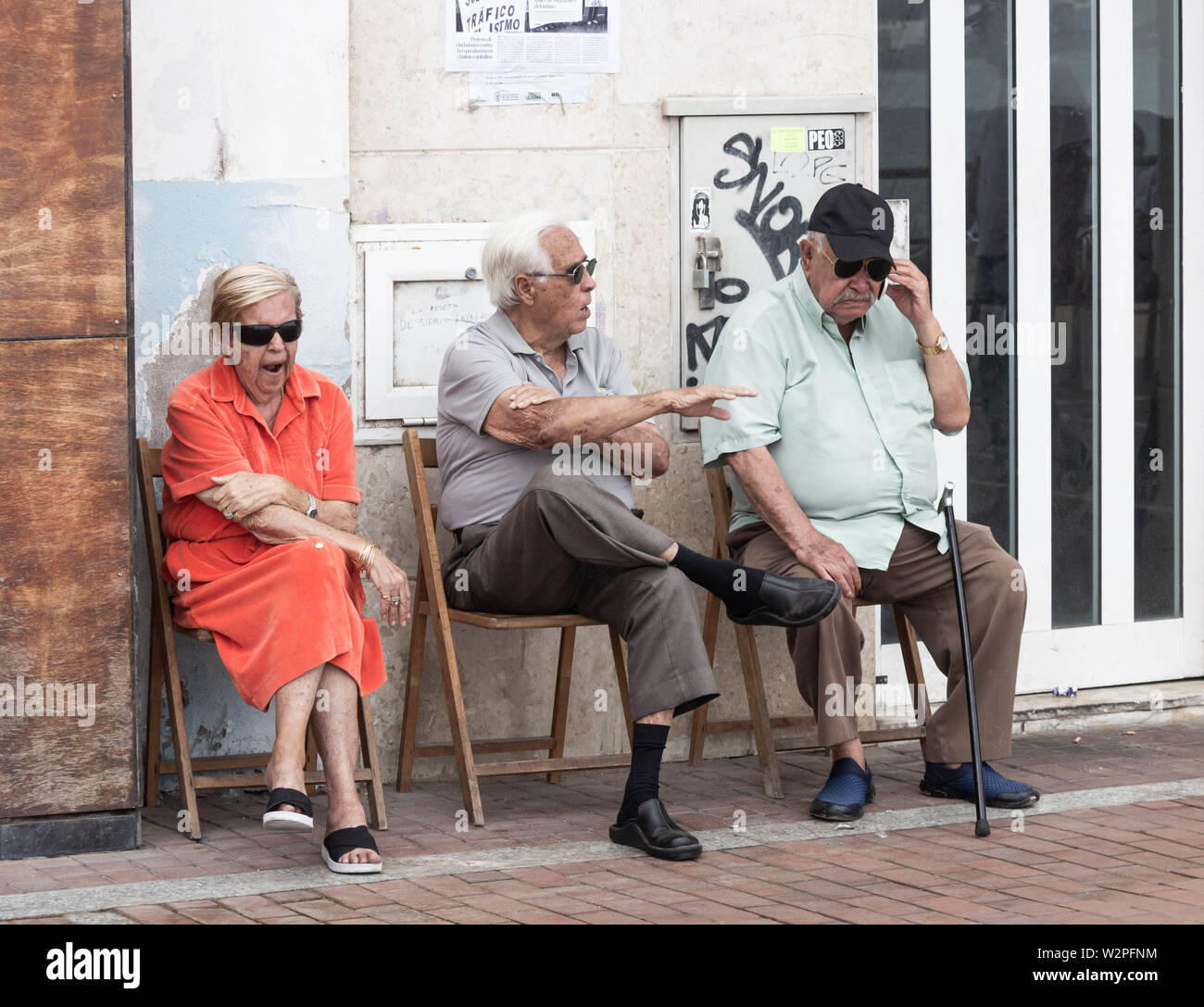 Two  elderly men and a woman sitting in street in Spain Stock Photo
