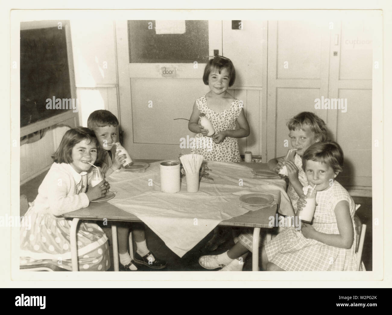 Original mid century, 1960's photograph of happy primary school children drinking free school milk from a bottle , possibly Leicestershire, U.K. Stock Photo