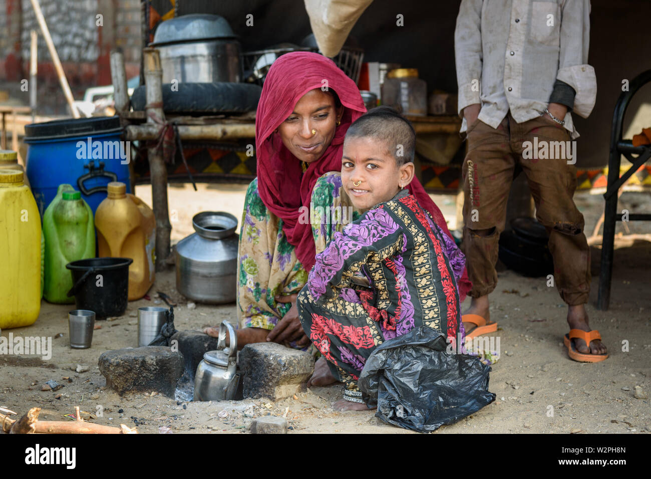 Ajmer, India - February 07, 2019: Indian woman with girl sitting on the street. Poor people come with family to the city from the village for work. An Stock Photo