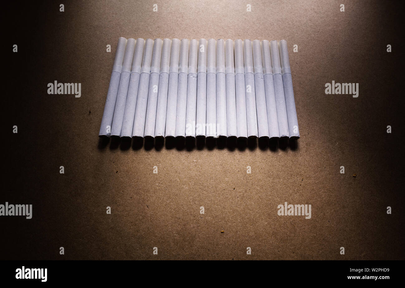 Abstract composition of bunch of cigarettes on brown surface. Stock Photo