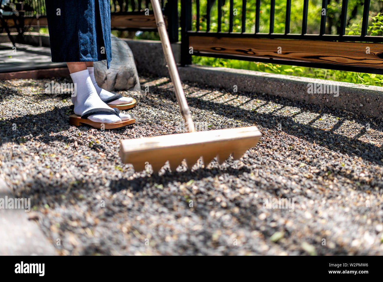 Feet of man in kimono costume and geta tabi shoes socks in outdoor garden raking rock garden in Japan Stock Photo