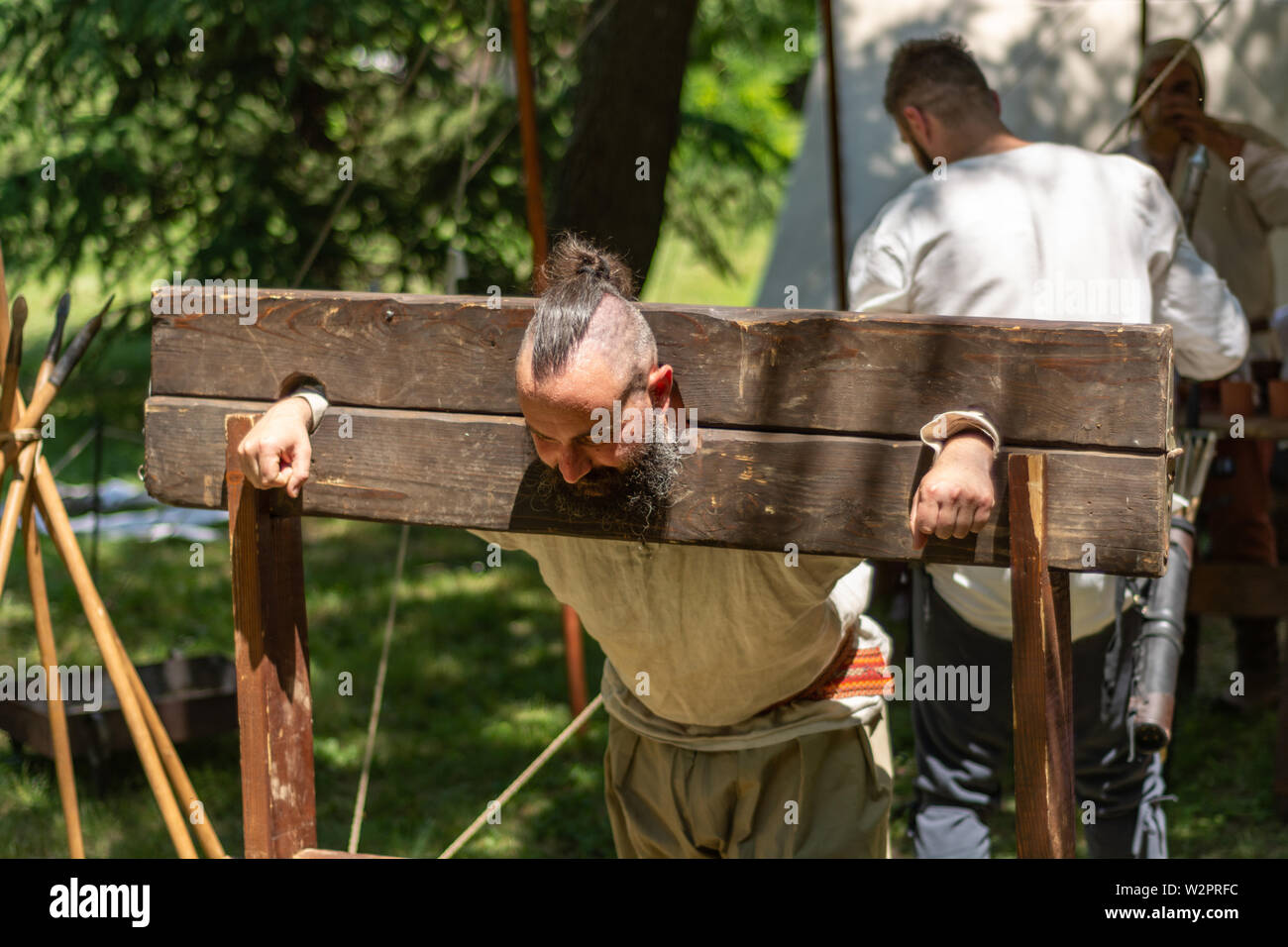 Nis, Serbia - June 15. 2019 Medieval prisoner in a wooden pillory of shame raped and tortured at an international knight festival. Close up Stock Photo