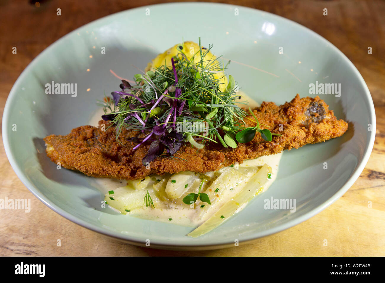 Deepfried fish, served in breadcrumbs, on a bed of onions and seasonal