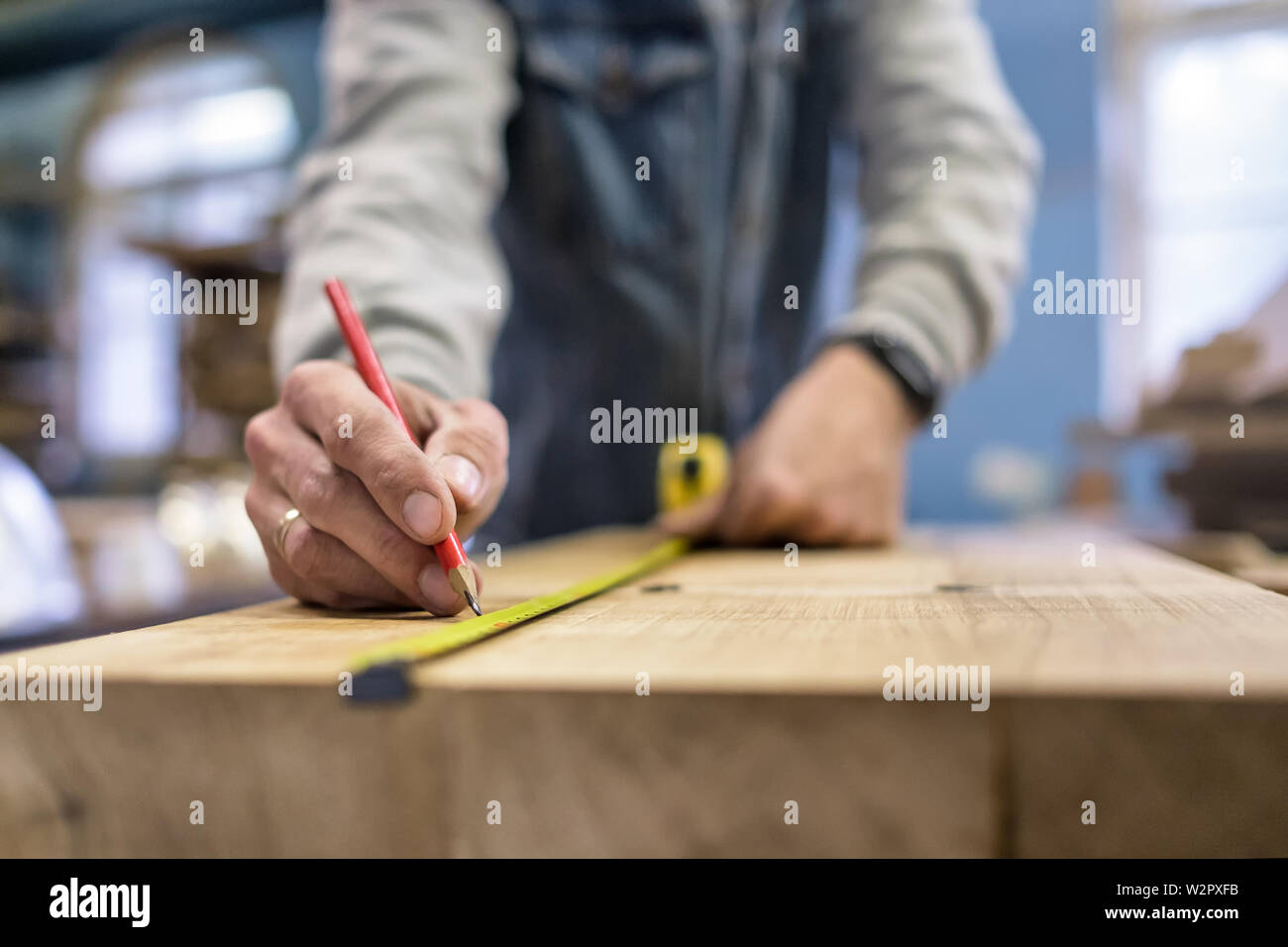 Carpenter measuring and tracing line with a ruler and pencil on wooden ...