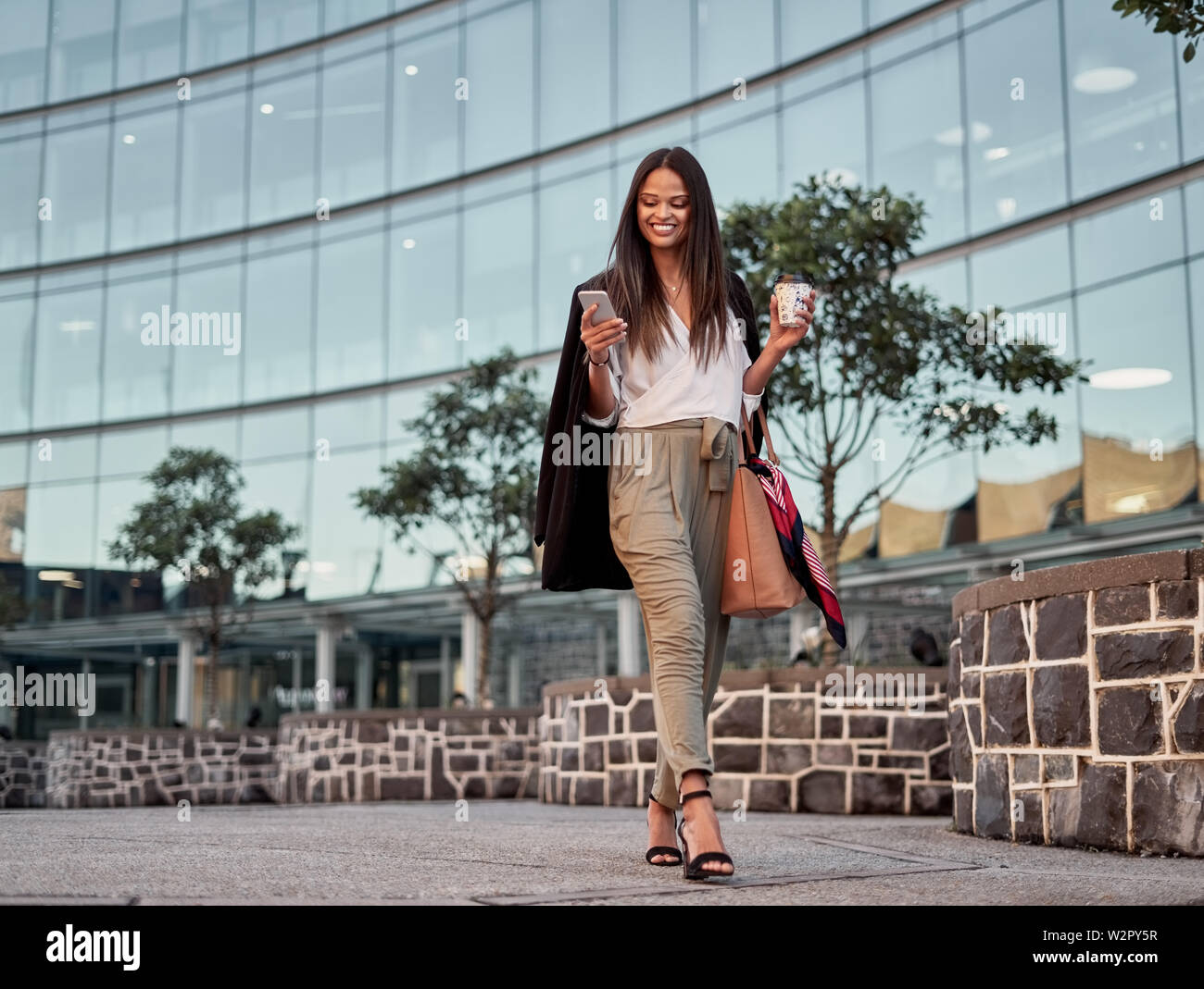Smiling young woman using cellphone outdoors in the city Stock Photo