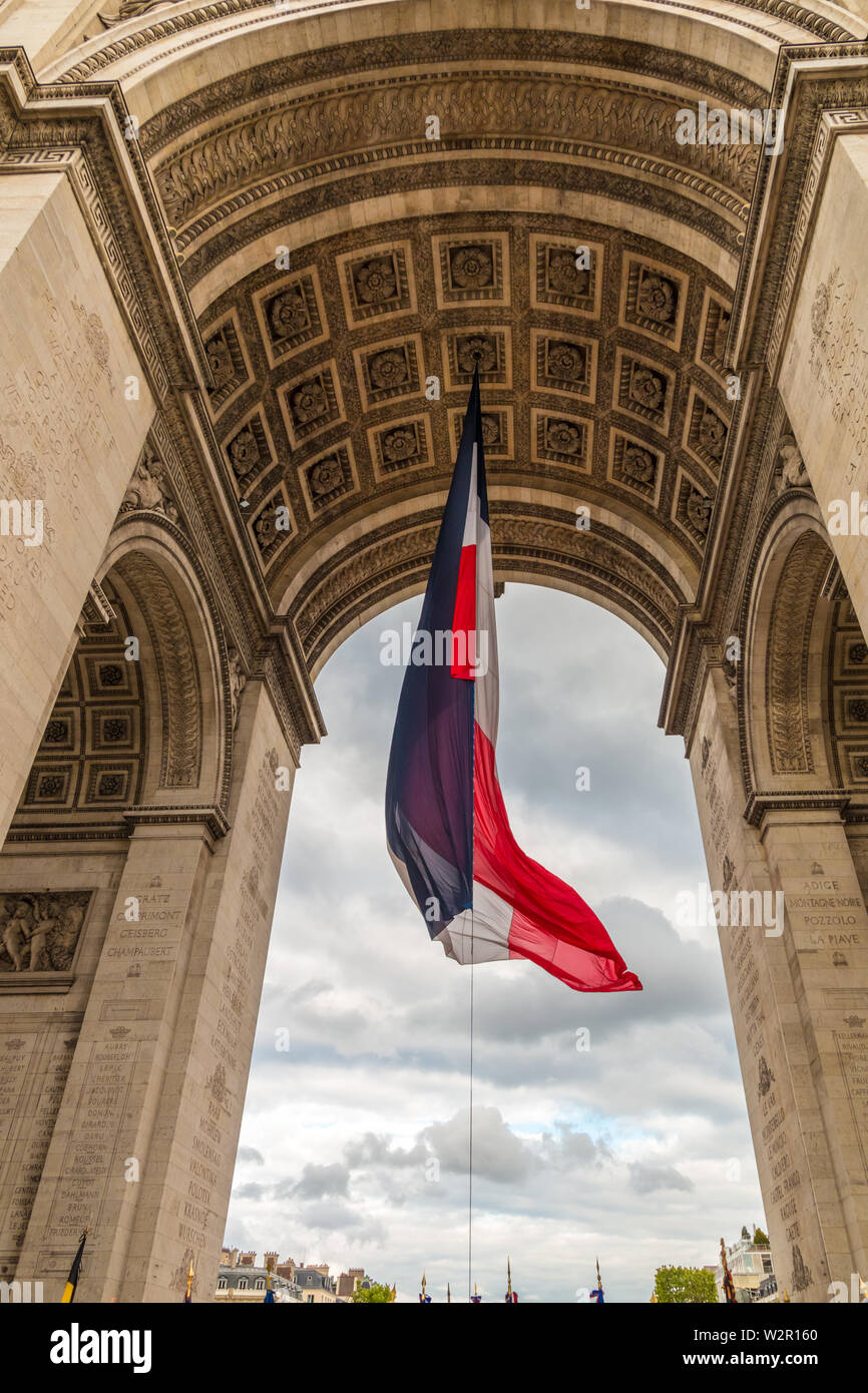 Close-up view under the Arc de Triomphe de l'Étoile in Paris with a large French flag during the ceremony to recall the sacrifice of an unknown French... Stock Photo