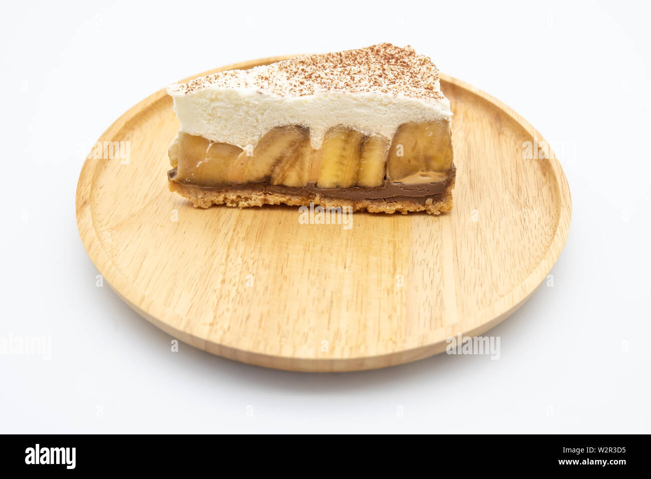 Banoffee Pie, whipped cream and banana on the wooden plate isolate ...