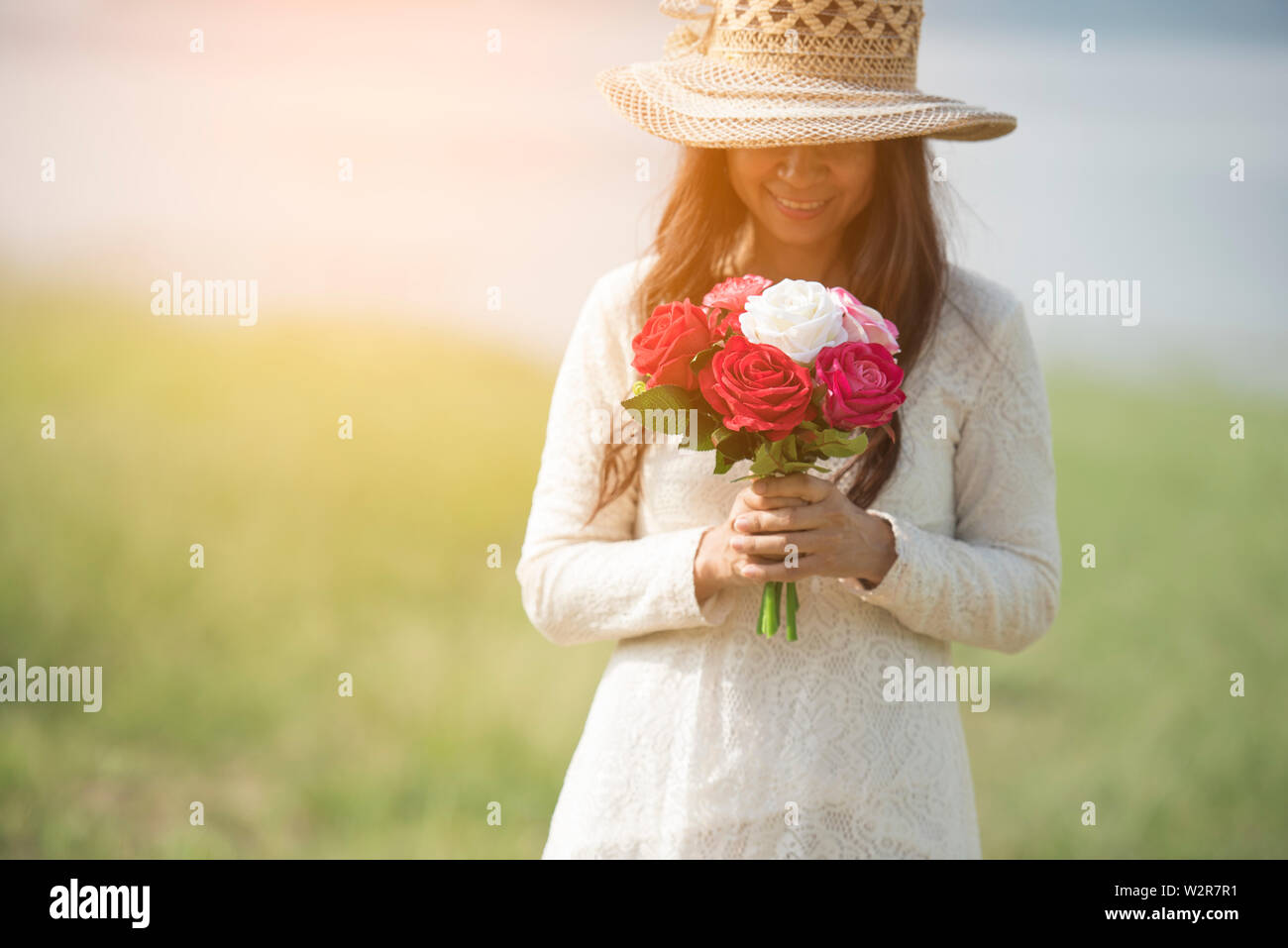 Holidays, love and flowers concept - young beautiful woman wear a white lace dress with bouquet of flowers. Stock Photo